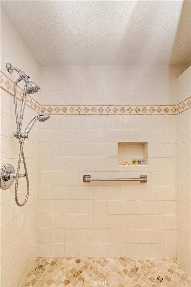 bathroom with tiled shower and a textured ceiling