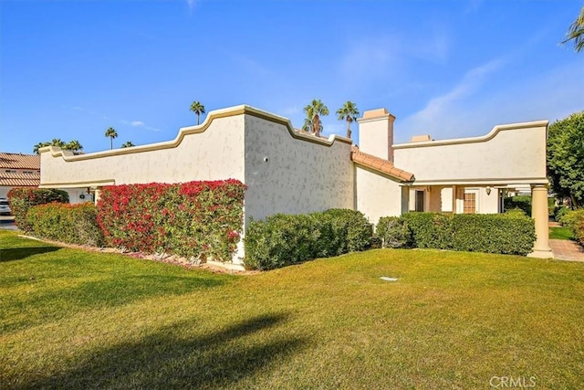 128 Desert Falls Dr E, Palm Desert, CA 92211 - view of side of property featuring a lawn, stucco siding, and a chimney
