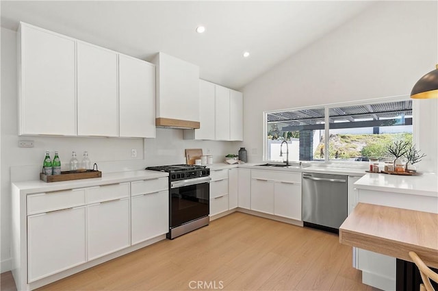 kitchen featuring custom exhaust hood, white cabinets, sink, appliances with stainless steel finishes, and light hardwood / wood-style floors