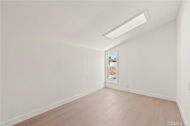 spare room with light wood-type flooring and lofted ceiling with skylight