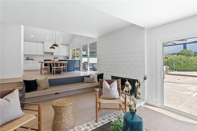 living room featuring sink, a fireplace, vaulted ceiling, and light wood-type flooring