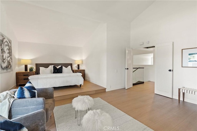 bedroom with hardwood / wood-style floors and high vaulted ceiling