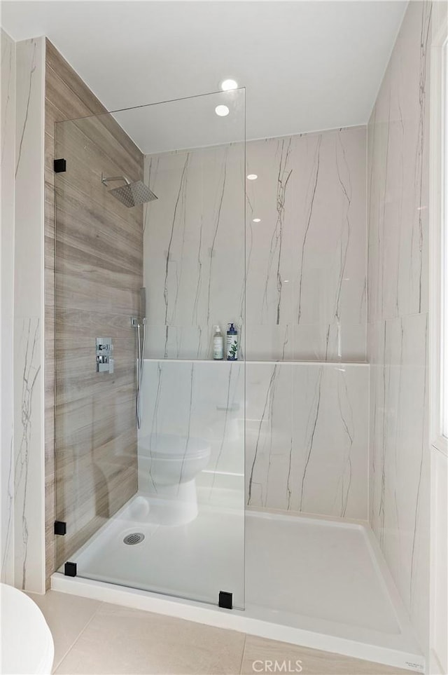 bathroom featuring toilet, tile walls, and tiled shower