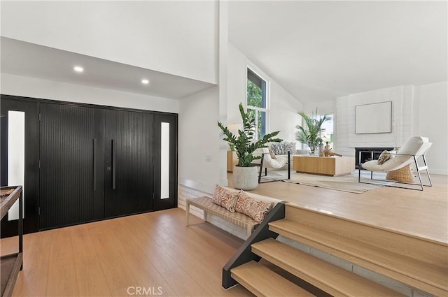 foyer with a fireplace, light hardwood / wood-style flooring, and high vaulted ceiling