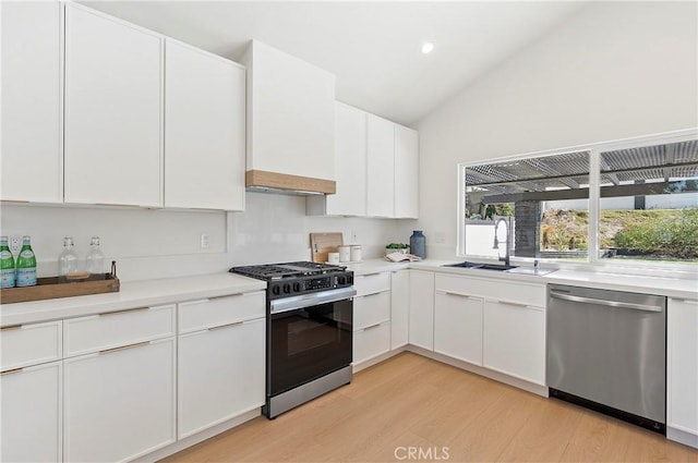 kitchen featuring white cabinetry, sink, vaulted ceiling, and appliances with stainless steel finishes