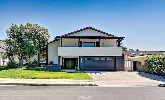 view of front of home featuring a balcony, a front yard, and a garage