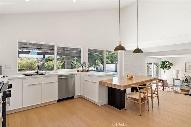 kitchen with pendant lighting, high vaulted ceiling, light hardwood / wood-style floors, white cabinetry, and stainless steel appliances