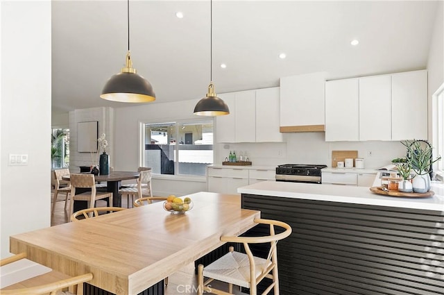 kitchen with decorative light fixtures, white cabinetry, and stainless steel range with gas cooktop