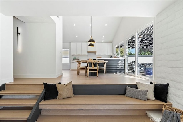 living room with light hardwood / wood-style floors, lofted ceiling, and sink