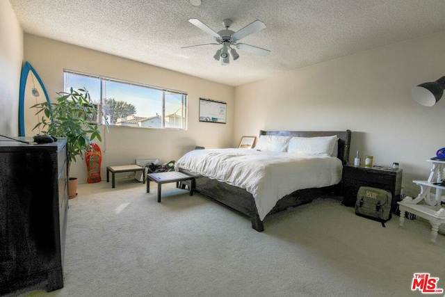 carpeted bedroom featuring ceiling fan and a textured ceiling