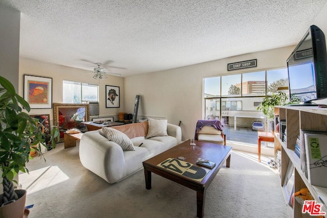 living room with a textured ceiling, ceiling fan, and light colored carpet