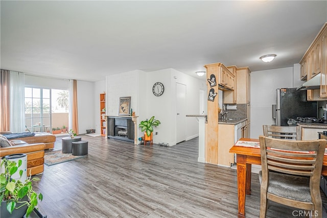 kitchen featuring tasteful backsplash, a fireplace, light brown cabinets, and hardwood / wood-style flooring