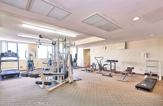 exercise room with carpet floors and a textured ceiling