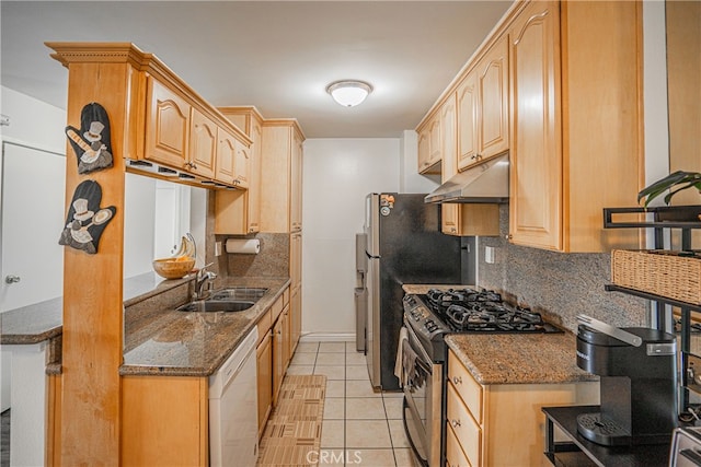 kitchen featuring gas range, sink, dark stone counters, white dishwasher, and light tile patterned floors