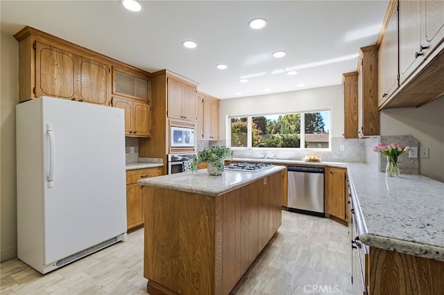 kitchen featuring decorative backsplash, light stone counters, stainless steel appliances, and a center island