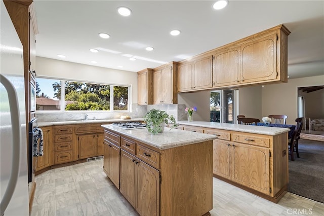 kitchen with a center island, tasteful backsplash, sink, kitchen peninsula, and stainless steel gas stovetop