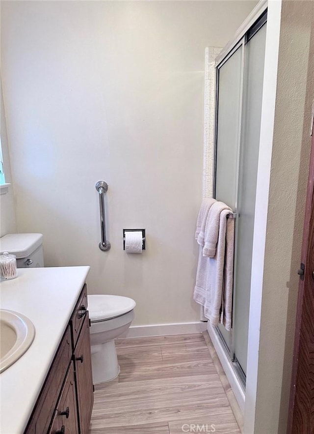 bathroom featuring toilet, a shower with shower door, wood-type flooring, and vanity