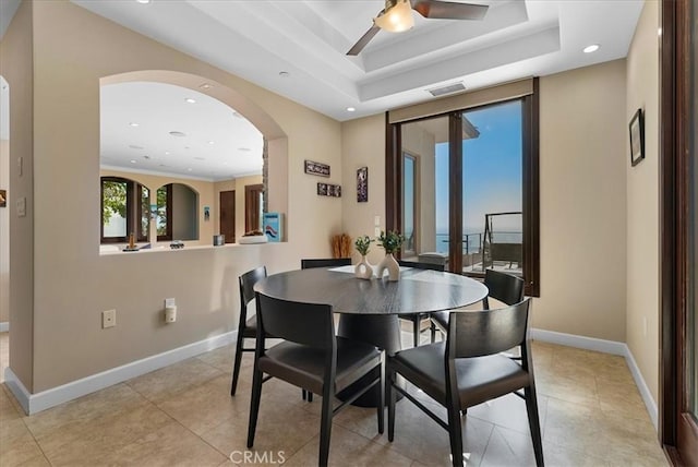 dining space with ceiling fan and a tray ceiling