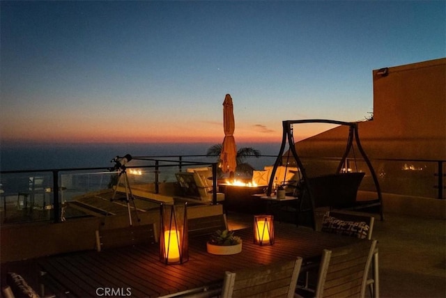 deck at dusk featuring a water view