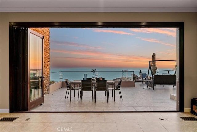 interior space featuring light tile patterned floors, crown molding, and a water view