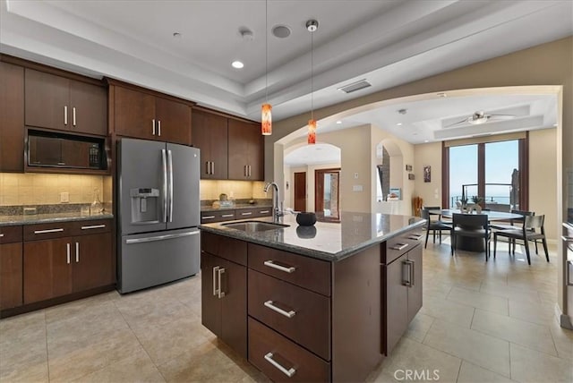 kitchen featuring stainless steel refrigerator with ice dispenser, black microwave, a raised ceiling, and sink