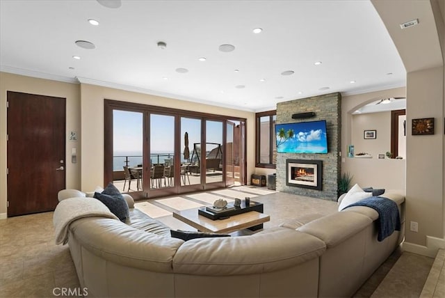 living room featuring ceiling fan, light tile patterned flooring, ornamental molding, and a fireplace