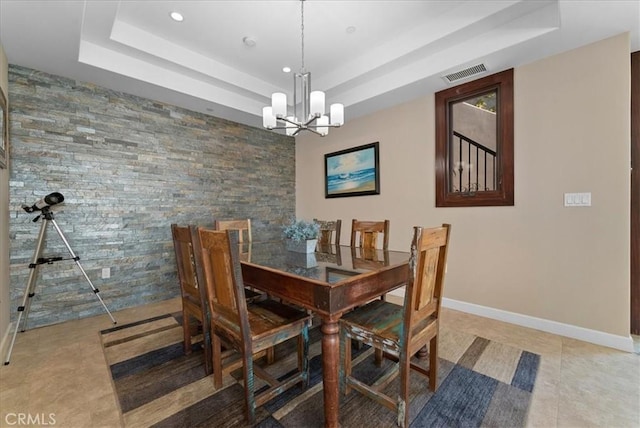 dining room featuring an inviting chandelier, light tile patterned floors, and a tray ceiling