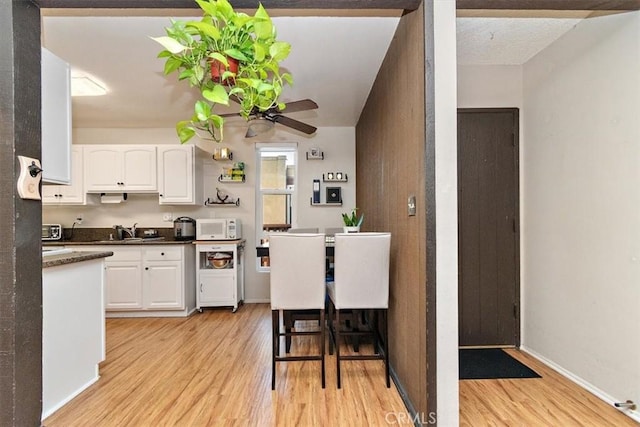 kitchen with ceiling fan, sink, light hardwood / wood-style floors, and white cabinetry