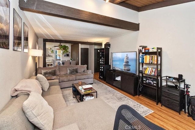 living room featuring beamed ceiling and light hardwood / wood-style floors