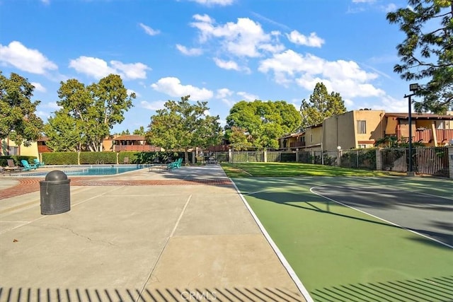 view of tennis court with a community pool and basketball hoop