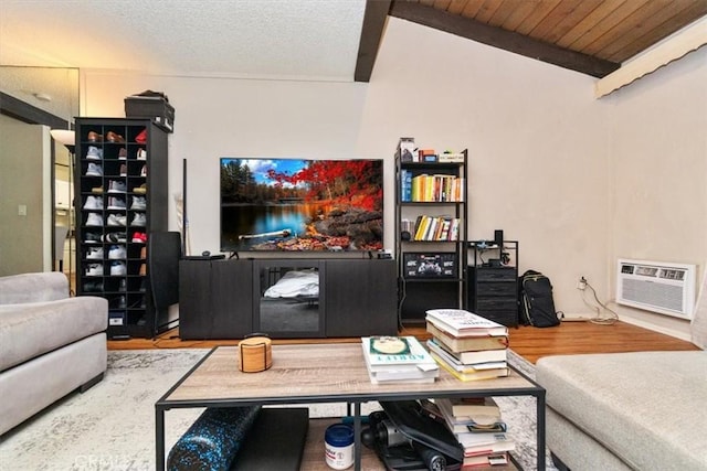 living room featuring hardwood / wood-style flooring, a wall mounted AC, a textured ceiling, and vaulted ceiling with beams