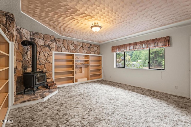 unfurnished living room featuring carpet flooring and a wood stove