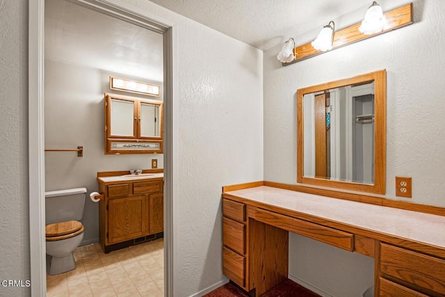 bathroom with vanity, a textured ceiling, and toilet