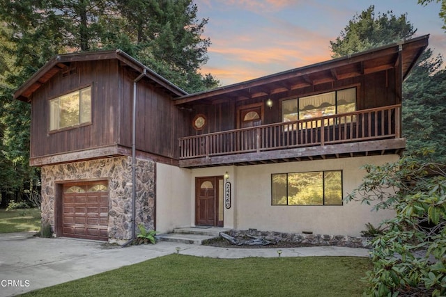view of front facade featuring concrete driveway, a front lawn, a balcony, and a garage