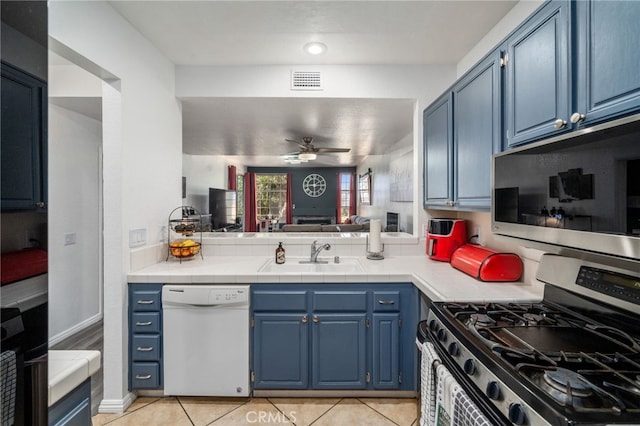 kitchen featuring appliances with stainless steel finishes, sink, blue cabinetry, ceiling fan, and light tile patterned floors