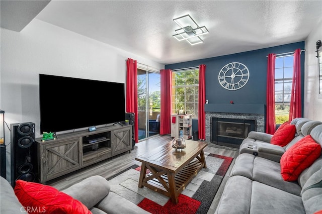 living room with a fireplace, light hardwood / wood-style floors, and a textured ceiling