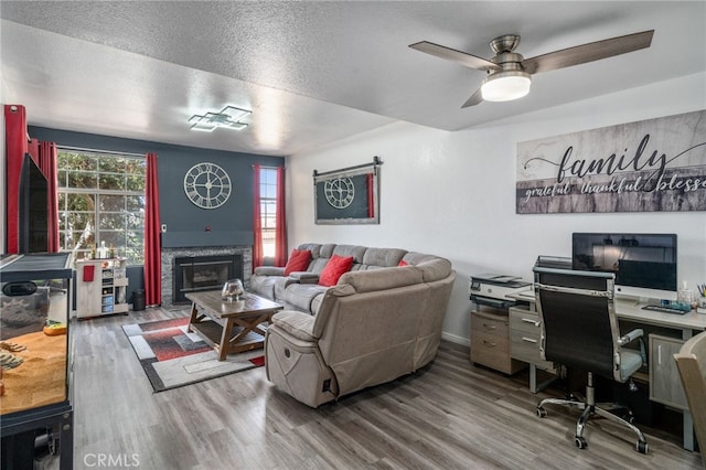 living room with a textured ceiling, ceiling fan, and hardwood / wood-style floors