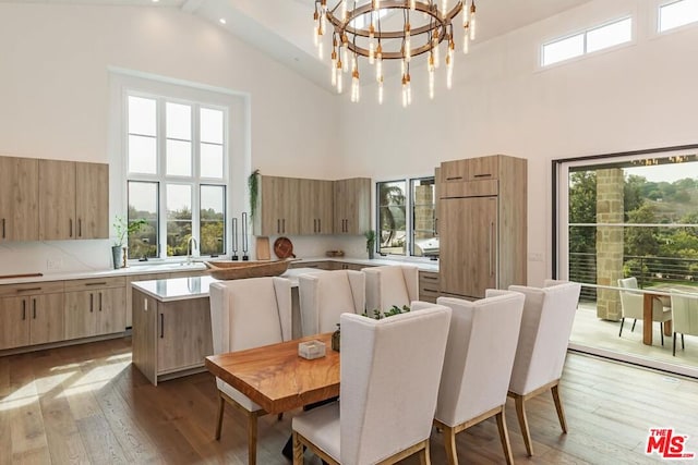 dining room with wood-type flooring, sink, beam ceiling, high vaulted ceiling, and an inviting chandelier