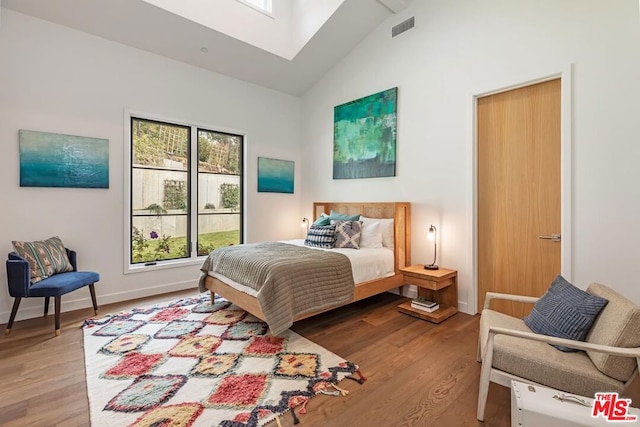 bedroom featuring wood-type flooring and high vaulted ceiling