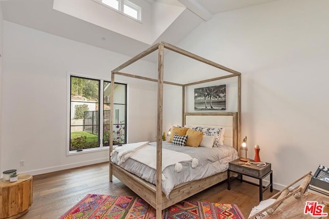 bedroom with high vaulted ceiling and hardwood / wood-style flooring