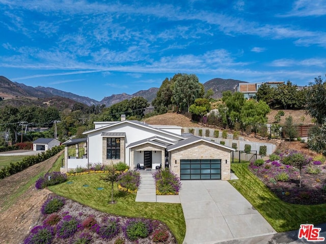 view of front of house with a front yard, a garage, and a mountain view