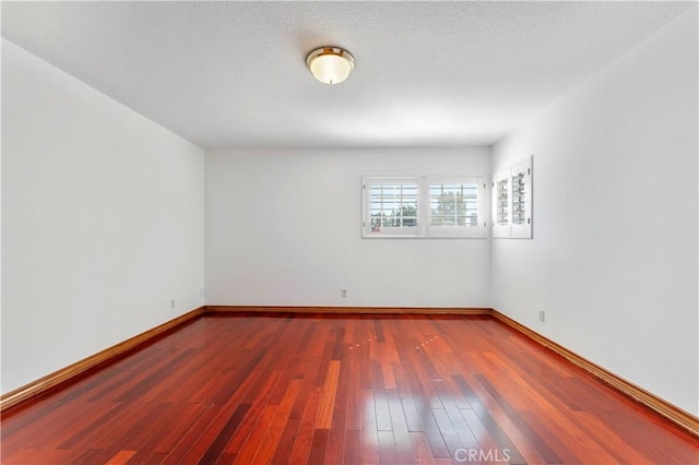 unfurnished room featuring dark hardwood / wood-style flooring and a textured ceiling