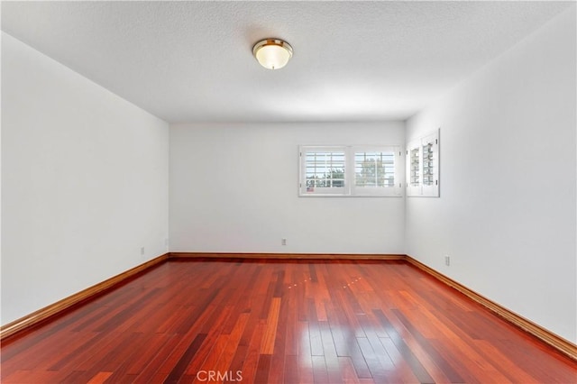 spare room featuring dark hardwood / wood-style floors and a textured ceiling