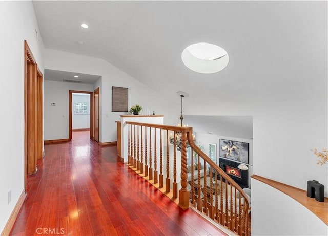 hallway with hardwood / wood-style floors and vaulted ceiling