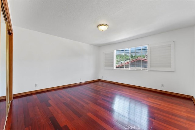 spare room featuring wood-type flooring and a textured ceiling