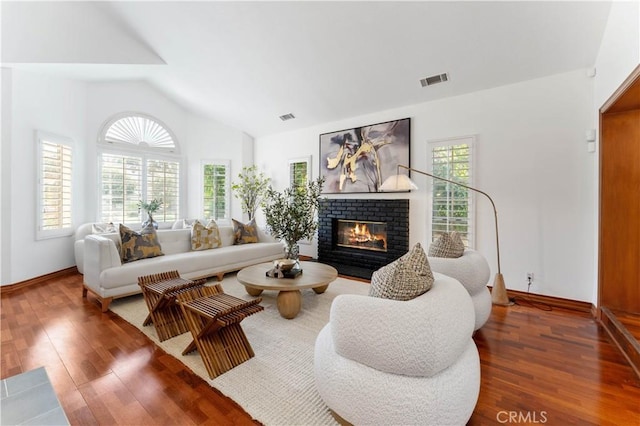 living room featuring dark hardwood / wood-style flooring, lofted ceiling, a wealth of natural light, and a brick fireplace