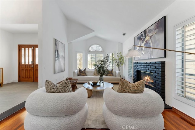 living room with a fireplace, hardwood / wood-style floors, a wealth of natural light, and lofted ceiling