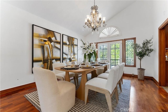 dining area featuring dark wood-type flooring, a chandelier, and high vaulted ceiling