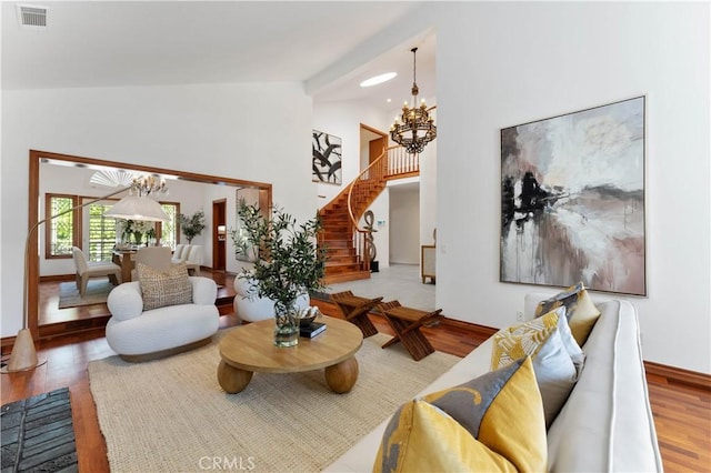 living room with lofted ceiling, hardwood / wood-style floors, and a notable chandelier