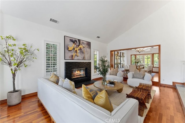 living room with hardwood / wood-style floors, a brick fireplace, and a wealth of natural light